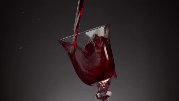 Pouring Red Wine Into a Shiny Glass Over a Black Background