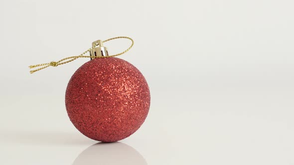 Christmas ornament on white background  4K 2160p 30fps UltraHD tilting  footage - Red shiny bauble w