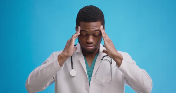 Professional Medical Doctor Suffering From Acute Migraine Attack, Blue Studio Background