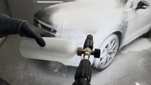 Man Covering a Car with Foam Using High Pressure Washer