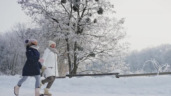 Mom with Daughter Running on a Snowy Road