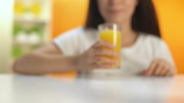 Brunette Woman Taking Glass of Orange Juice From Table and Drinking, Vitamin C