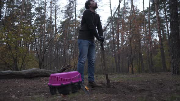 A Sad Man is Digging a Grave with a Shovel for a Pet Mitt