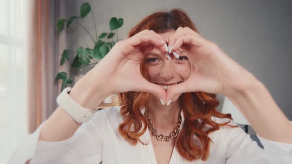 Redhead Woman in Love Holding Heart Sign with Hand on the Eve of Valentine