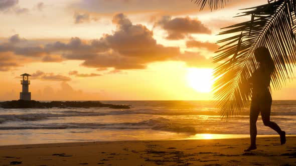 Young Woman Exercising Running Barefoot on Sea Beach with Sunset Ocean Background