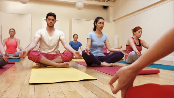 Instructor assisting a group of people in yoga