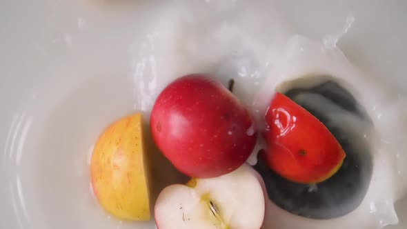 Apple slices falling into milk with a big splash into peaces. Topview close up shot.