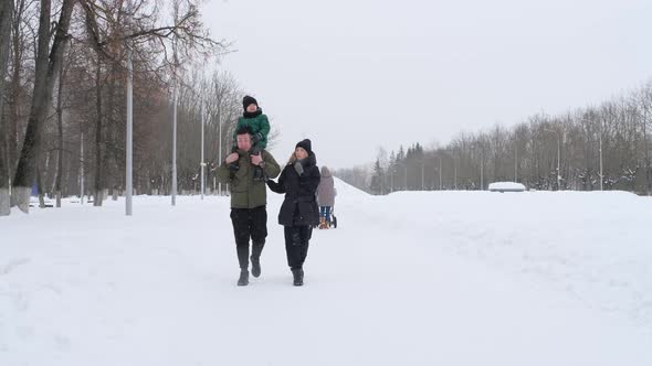 Dad Carries His Son on His Shoulders and Mom Walks Beside