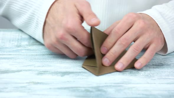 Hands Doing Origami Toy From Brown Paper.