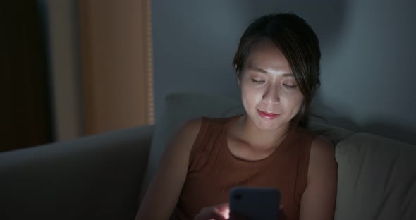 Woman use of mobile phone at home in the evening