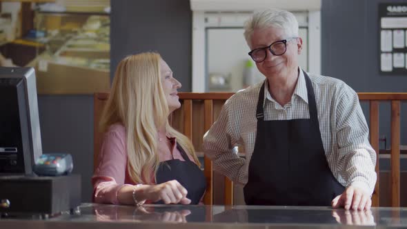 Mature Couple of Cafe Owners Standing at Counter and Smiling at Camera