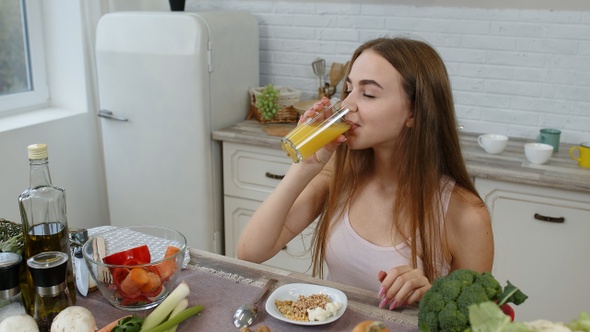 Girl Eating Raw Sprouts Buckwheat with Nuts, Drinking Orange Juice in Kitchen. Weight Loss and Diet