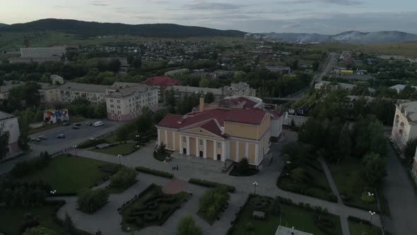 Aerial view of beautiful house of culture square and alley. People walk, cars drive on roads 12