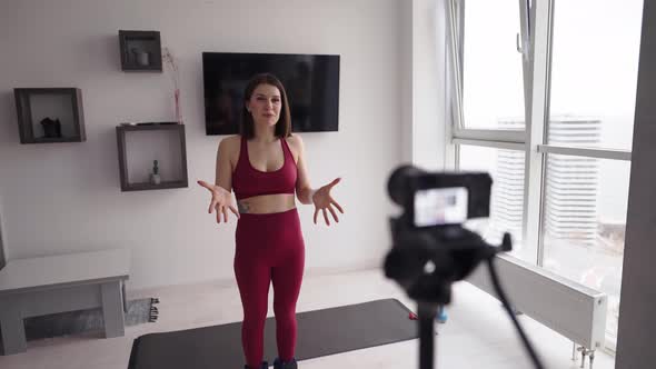 A Young Woman Fitness Instructor Records a Tutorial on Home Workouts on Camera