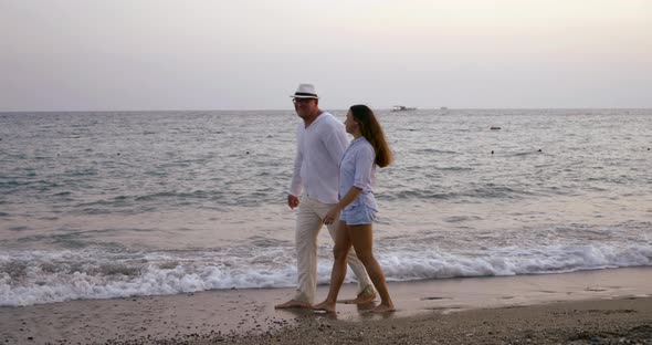 Romantic Pair Is Dancing on Shore of Sea in Evening, Woman Is Whirling, Man Is Embracing