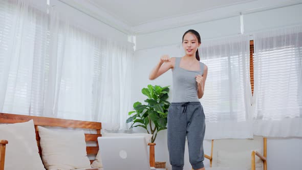 Asian Sporty young woman workout exercising by watching fitness live video tutorial Tv online.