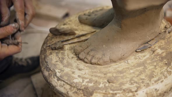 Close Up of Clay Buddha's Statue Feet Artist Works with Detail Using Tools