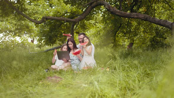 Positive Caucasian Family Having Summer Picnic with Sweet Fruits and Cupcakes