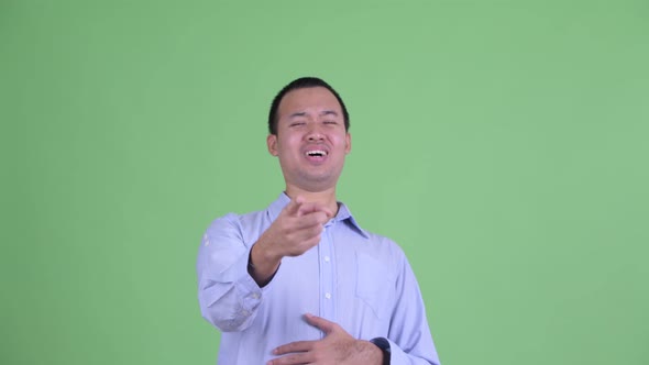 Studio Shot of Happy Asian Businessman Laughing and Pointing at Camera