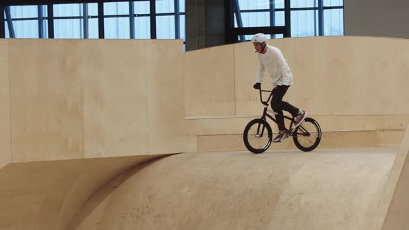 Young Man Rides on Bike Down the Ramp