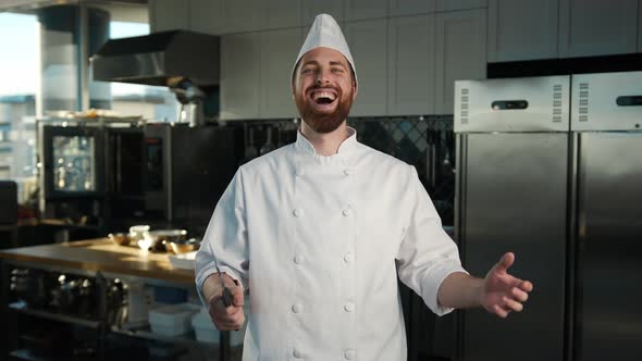 Professional kitchen, portrait: Male Chef holding a knife and laughing ominously