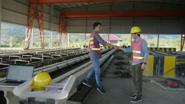 Construction Workers Shaking Hands And Talking At Construction Site