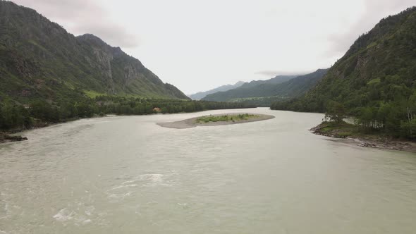 A Small Stone Island in the Middle of a Wide River in a Mountainous Area