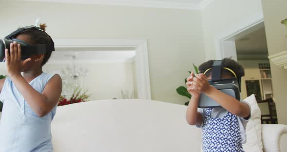 Happy african american girls using vr headsets in living room