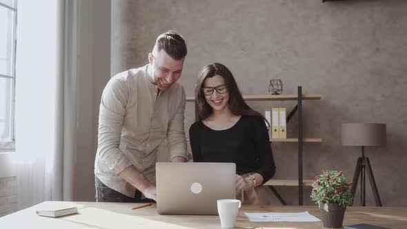 Office Worker Man and Woman Smiling Standing Near Laptop at the Table