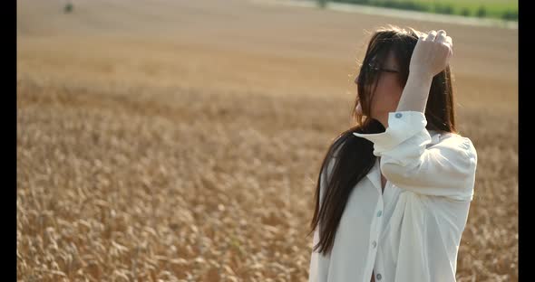 Beautiful Brown Hair Young Woman on Summer Wheat Field