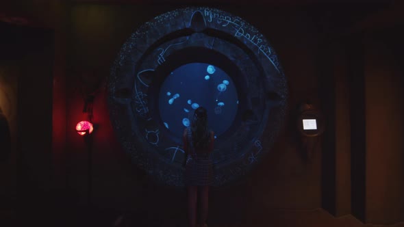 Slow Motion Forward View of Young Woman Leaning on Circular Glass of Large Fish Tank to Watch Smack