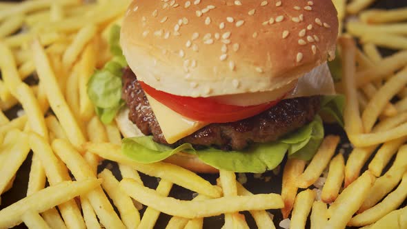 Delicious Cheeseburger Surrounded By French Fries on a Black Table