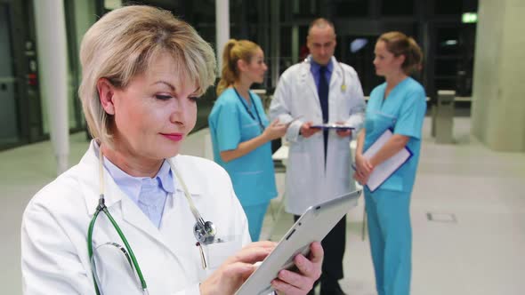 Smiling female doctor using digital tablet in hospital corridor