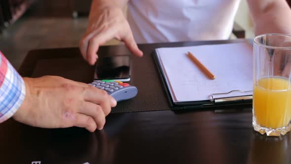 A male customer pays using NFC contactless payment technology on a smartphone.