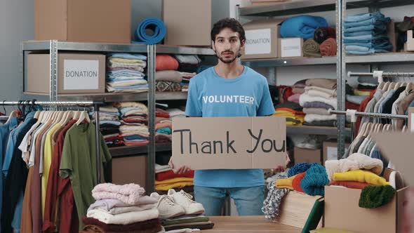 Portrait View of the Caucasian Volunteer Man Holding Banner with Thank you Phrase and Looking at the