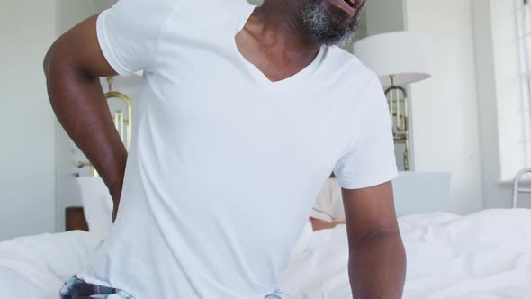 African american senior in bed man getting up with back pain