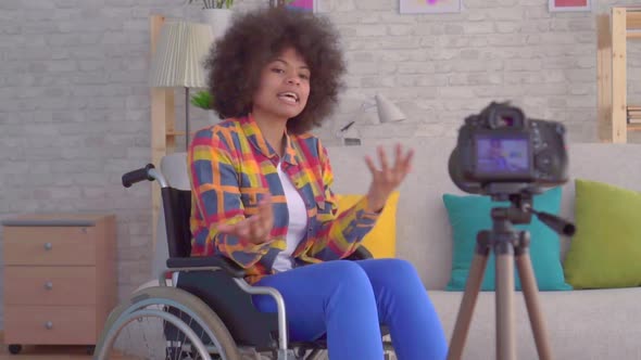 African Woman Blogger Disabled in a Wheelchair with an Afro Hairstyle Records Video Sitting in Front