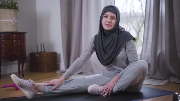 Portrait of Young Muslim Woman Looking at Camera and Smiling. Sportive Woman in Hijab and Sportswear