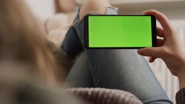 Young Woman Touching Smartphone Green Screen While Resting on the Sofa