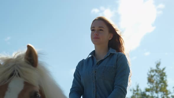 Redheaded woman riding a horse against bleu sky