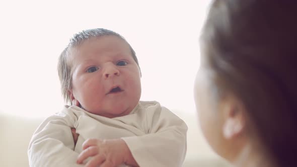 Newborn baby boy and his mother at home. Close-up portrait of the infant