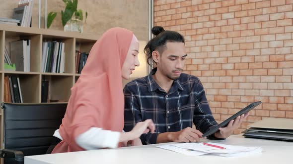 Two young Islamic couples work in a small startup office.