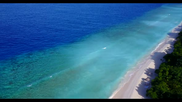 Aerial above seascape of tropical tourist beach lifestyle by shallow ocean and white sandy backgroun