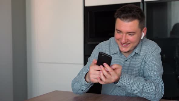 Portrait shot of the excited attractive man 30s dressed in shirt sitting at home and playing games