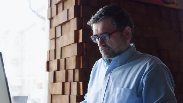 Senior Man Studies Documents Sitting in a Cafe