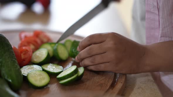 Closeup Female African American Hands Slicing Cucumber on Cutting Board