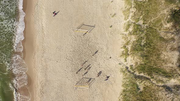 AERIAL: Young People Plays Football on a beach in Summer