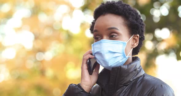 Head Shot African American Young Beautiful Woman in Medical Mask Talking on Mobile Phone and