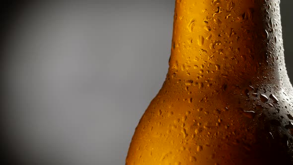 Brown Glass Beer Bottle Rotating Over Dark Background. Close-up Shot, 