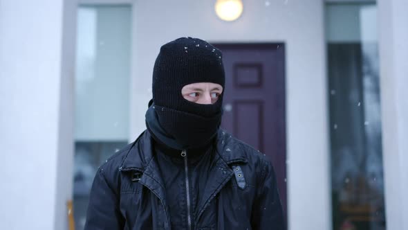 Portrait of Suspicious Caucasian Masked Man Looking Around Standing on Snowy Winter Day Outdoors